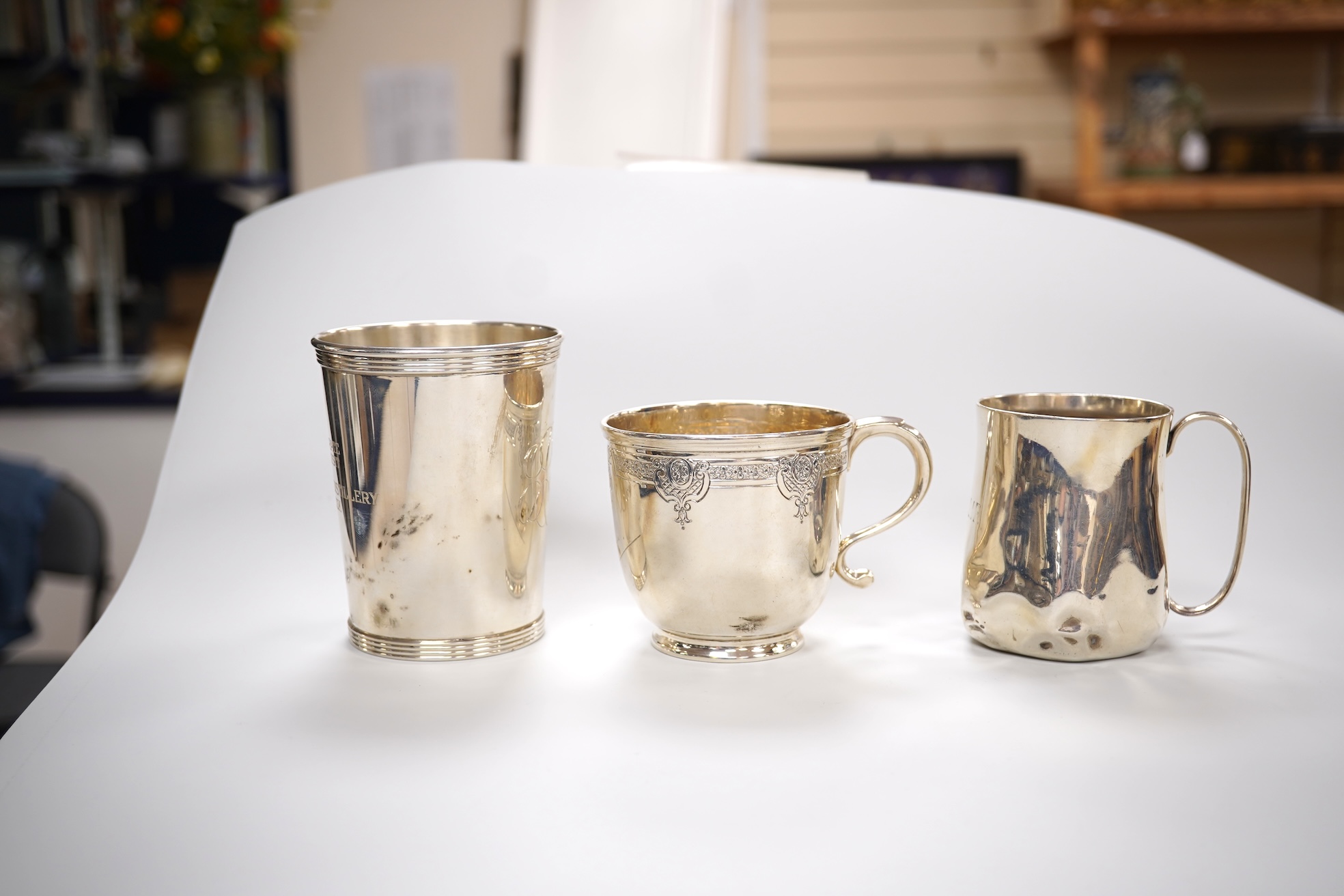 A George V engraved silver tea cup by Mappin & Webb, London, 1924, height 69mm, together with a Gorham sterling beaker and an Edwardian silver christening mug, 11oz.